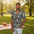 Man wearing printed shirt with Daisy Dragonfly Wings as petals design at a park with a picnic blanket behind him.
