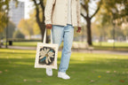 Person holding a tote bag with a floral design at a city park