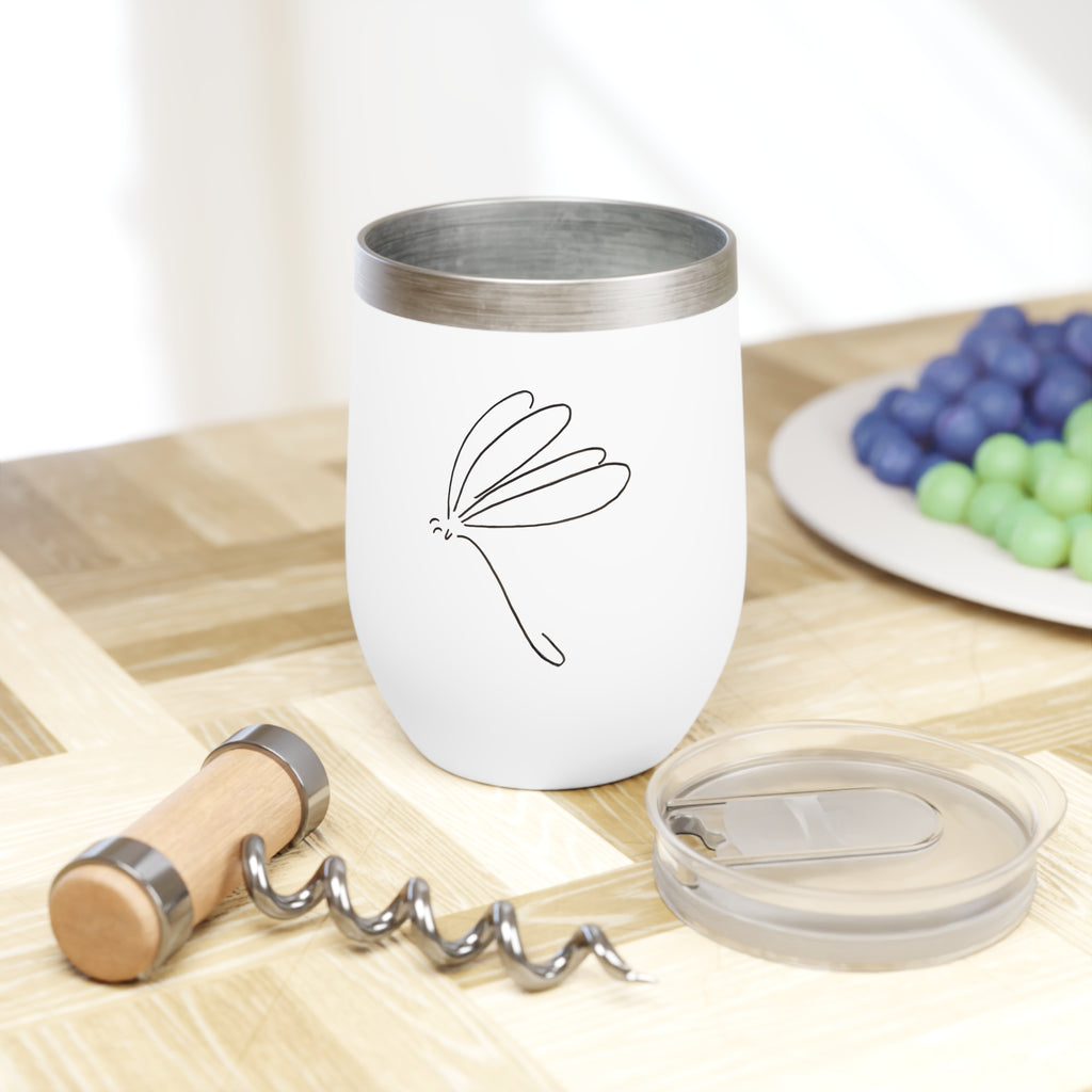 White tumbler with purple text on a wooden table with grapes and a corkscrew.