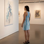 Woman wearing a mini dress with dragonfly wings design looking at an artwork.
