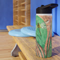 Waterbottle with dragonfly design on a wooden surface against a blue wall.
