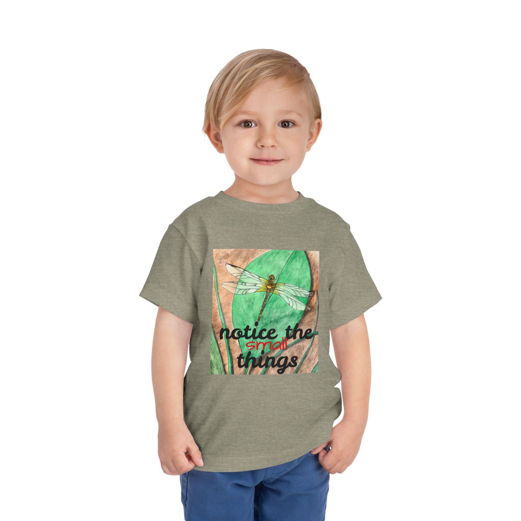 Child wearing a green t-shirt with a dragonfly graphic and text on a white background
