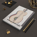 Notebook with a lute illustration and text 'when art meets music' on a dark surface with stationery items.
