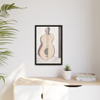 Framed artwork of a classical guitar on a wall above a desk with a plant and books.