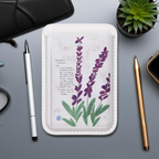 Small white book with floral design on a gray surface with stationery items.