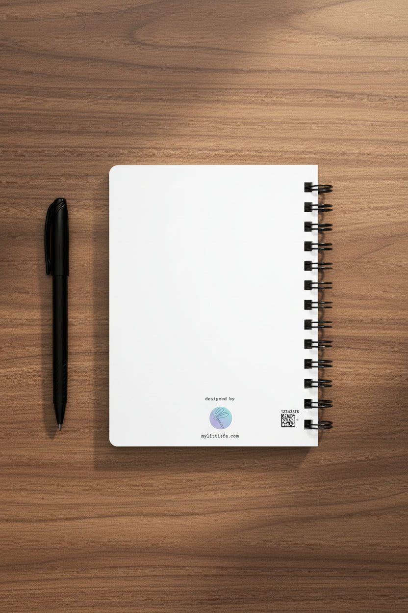 back of notebook with black spiral binding on a medium brown desk with a pen next to it