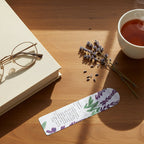 Decorative bookmark with lavender design and text on desk with hot drink, a book with reading glasses