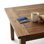 Mt. Rainier coaster with a hand holding a coffee mug next to it on a rustic coffee table