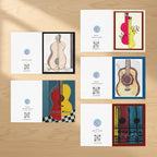 A set of printed guitar-themed cards or art prints arranged on a white background. The designs include painted and illustrated acoustic guitars in cream, red, yellow, blue, and black, with QR codes and small circular logos on several cards.