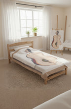 Blanket with half guitar half woman design in a bedroom with windows  with artpiece on an easel of same design 