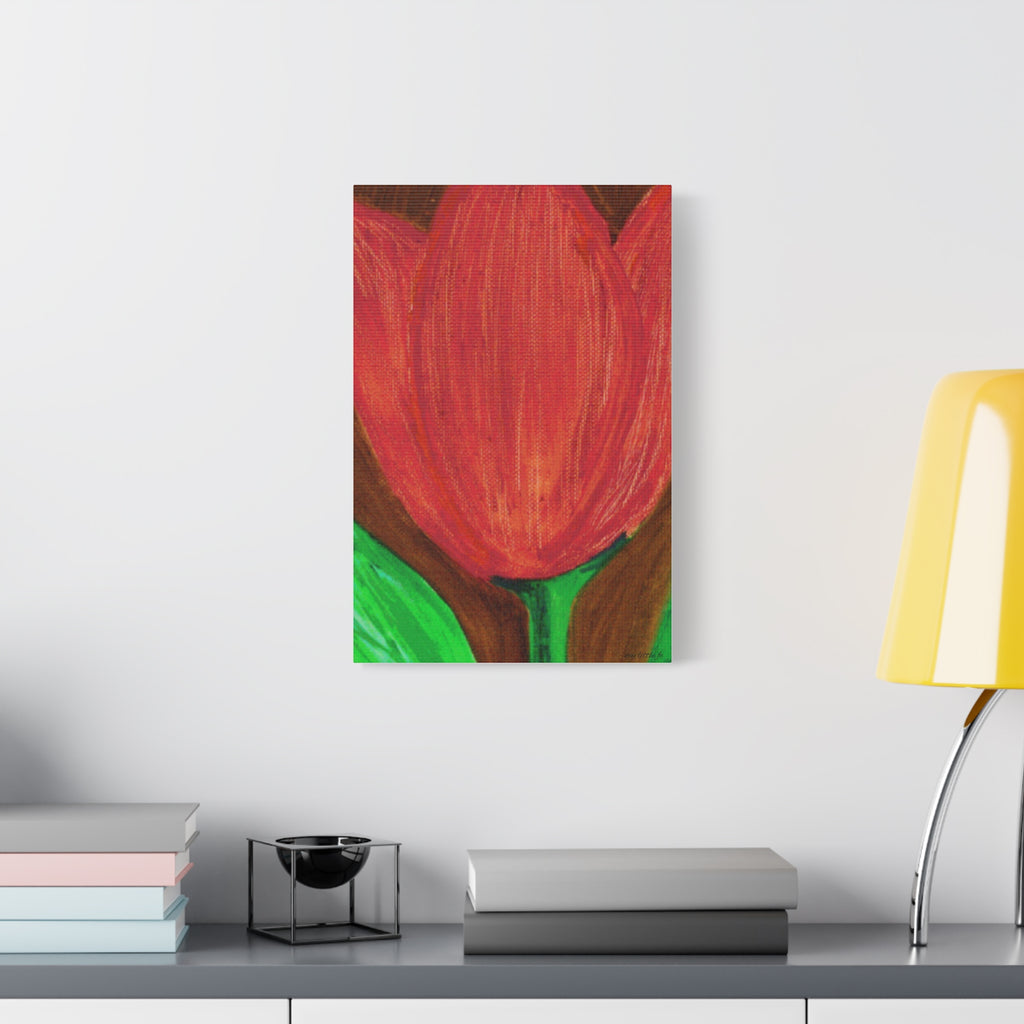 Framed artwork of a red tulip on a wall above a desk with books and a lamp.