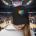 Black cap with a rainbow heart and 'spread kindness' text at a basketball stadium