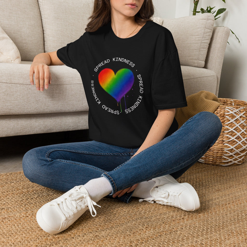 Person wearing a black t-shirt with a rainbow heart design and 'Spread Kindness' text, sitting on the floor.
