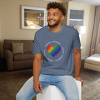 Man wearing a blue t-shirt with a rainbow heart design sitting in a living room.