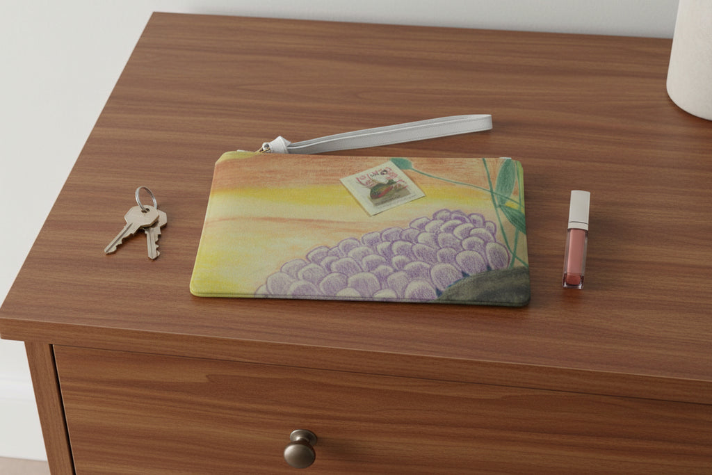 Clutch bag with ocean floor design and a sunfish stamp design on top of a dresser with keys and lip gloss next to it.