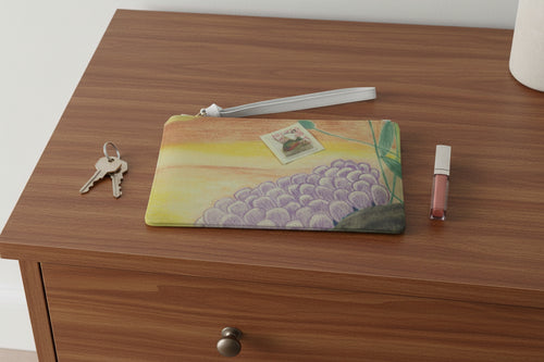 Clutch bag with ocean floor design and a sunfish stamp design on top of a dresser with keys and lip gloss next to it.