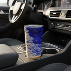 A tall insulated tumbler with a blue and white marbled wave pattern sits in a car cup holder, with the steering wheel and dashboard blurred in the background.