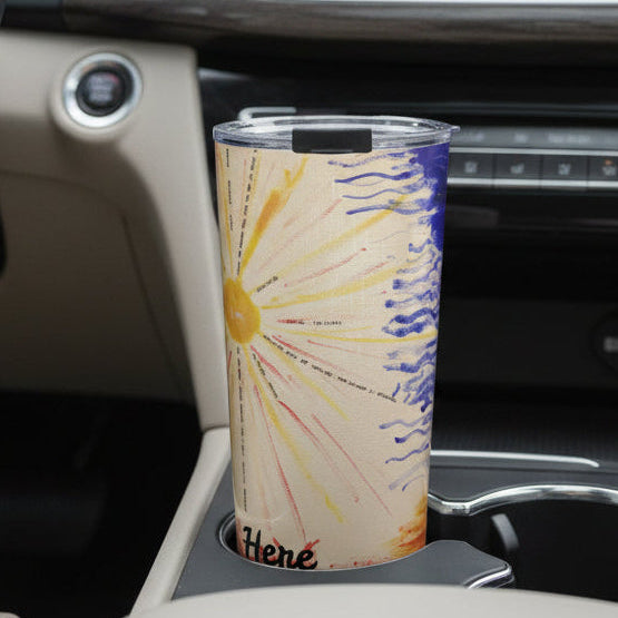 Colorful tumbler with a sunrise and clouds design with small quotes in a cup holder in a car
