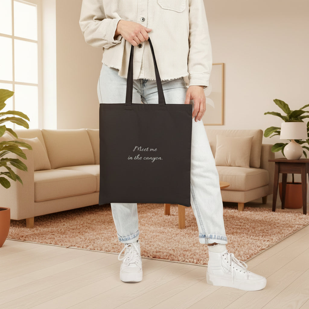 Person holding a black tote bag with 'Limitless' branding in a living room
