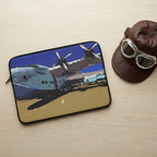 Laptop sleeve with a design of a vintage airplane on a light wood desk with a pilot's cap next to it
