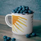 White mug with sun design filled with blueberries on a wooden surface.