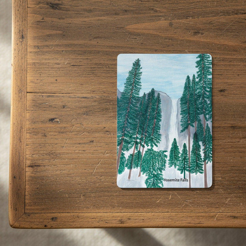 Playing card of Yosemite Falls design featuring trees and mountains on top a coffee table