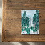 Playing card of Yosemite Falls design featuring trees and mountains on top a coffee table