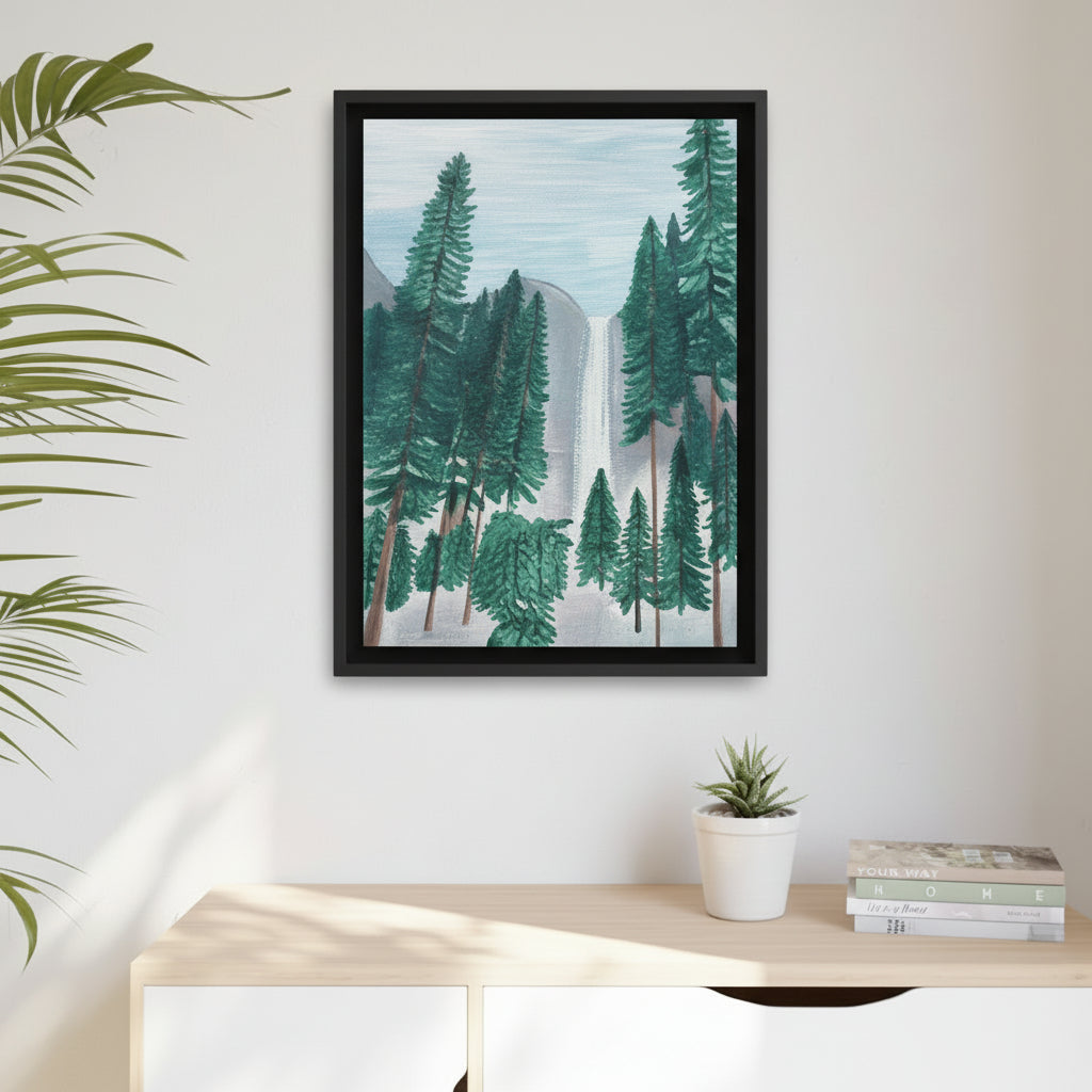 Framed artwork of a trees at Yosemite with waterfall scene on a wall above a desk with a plant and books.