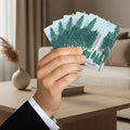 Hand holding a set of playing cards with Yosemite Tress  design on a living room background