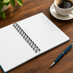 Open spiral-bound notebook with lined pages on a medium wood grain desk with a pen and coffee next to it.