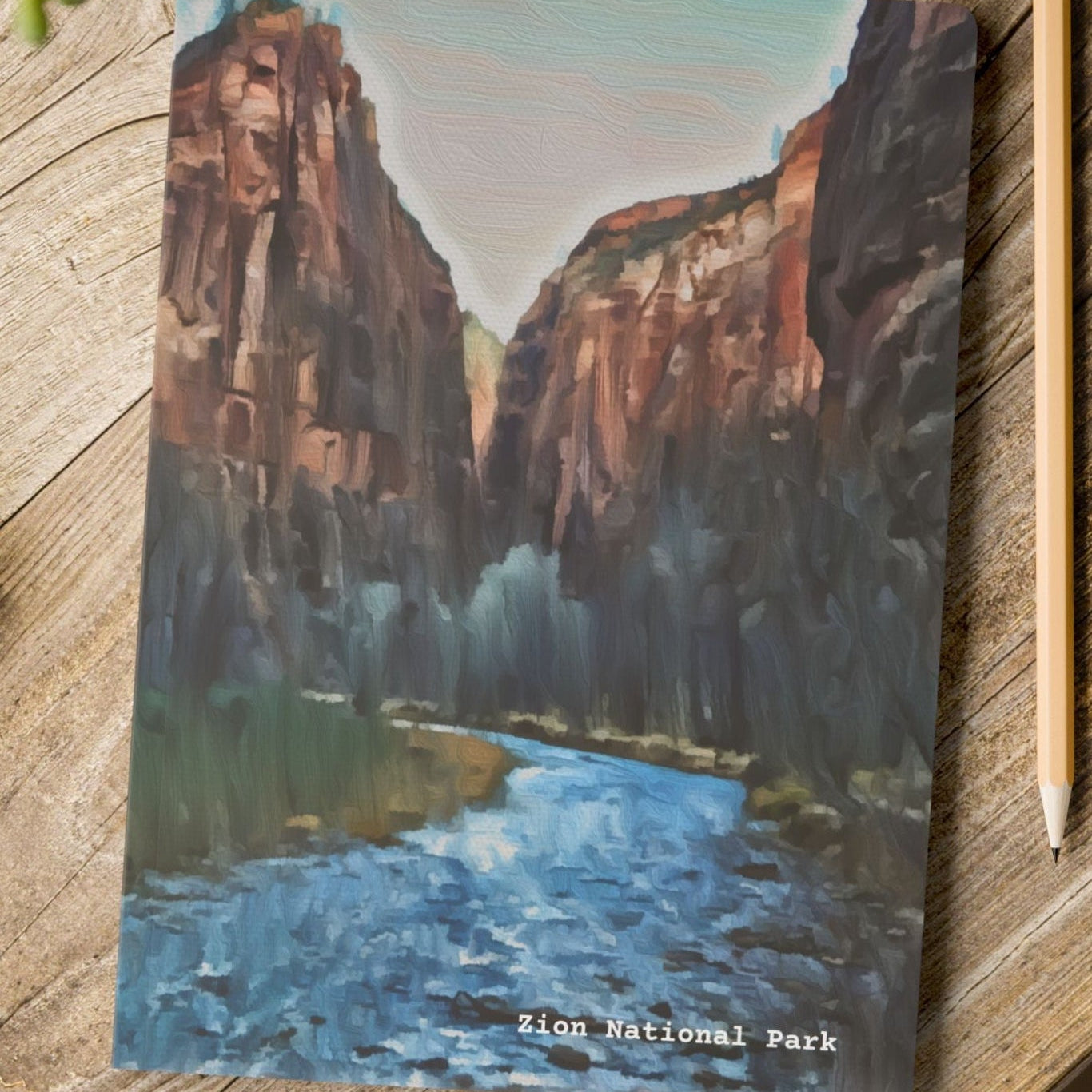 Notebook with Zion National Park design on a wooden surface with a pen and pencil.