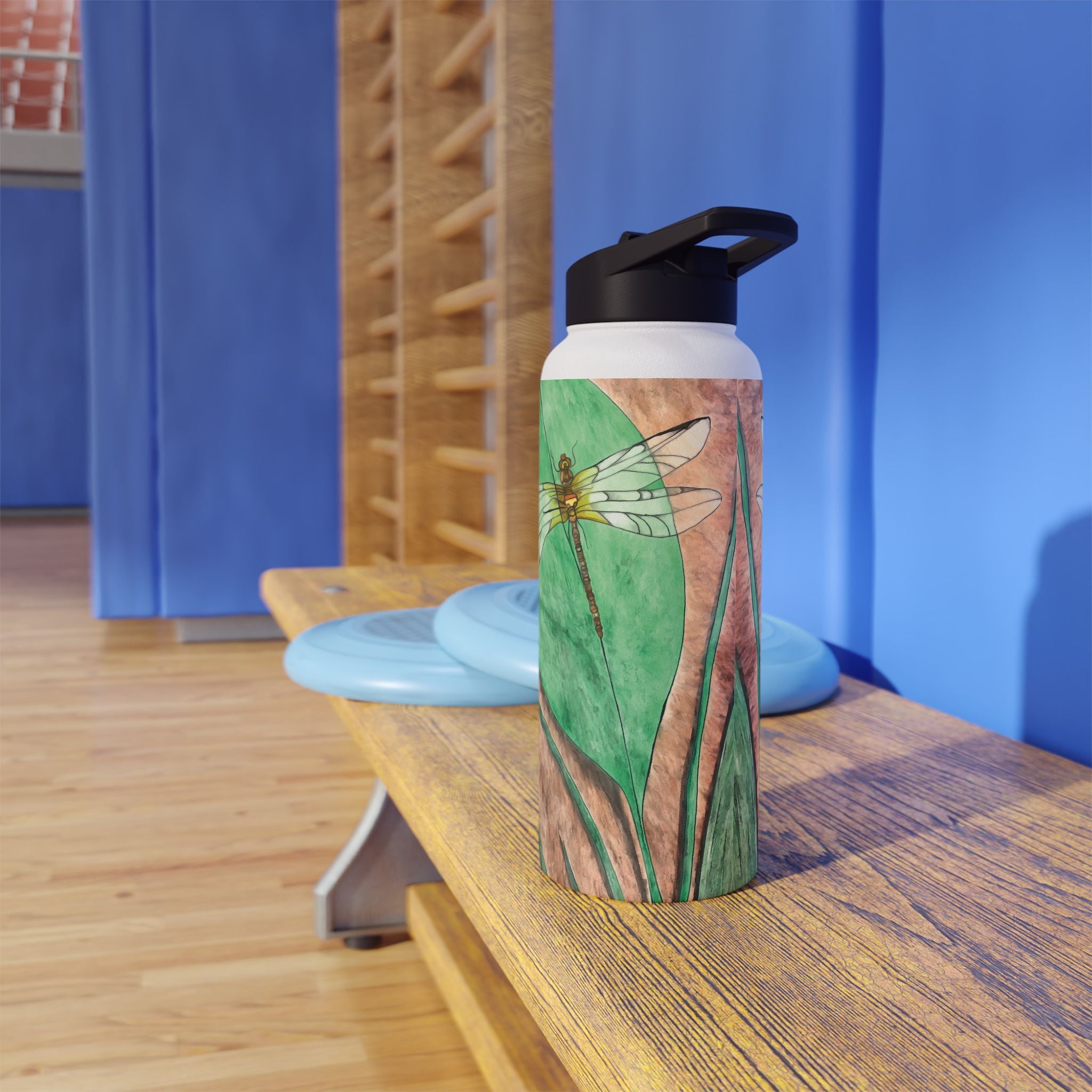 Water bottle with a dragonfly design on a wooden bench against a blue wall.