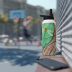 Person holding a water bottle with a dragonfly design at an outdoor event.