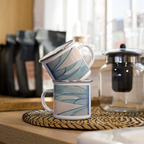 Two mugs with blue dragonfly wings designs stacked on a wooden surface with coffee-making equipment in the background.