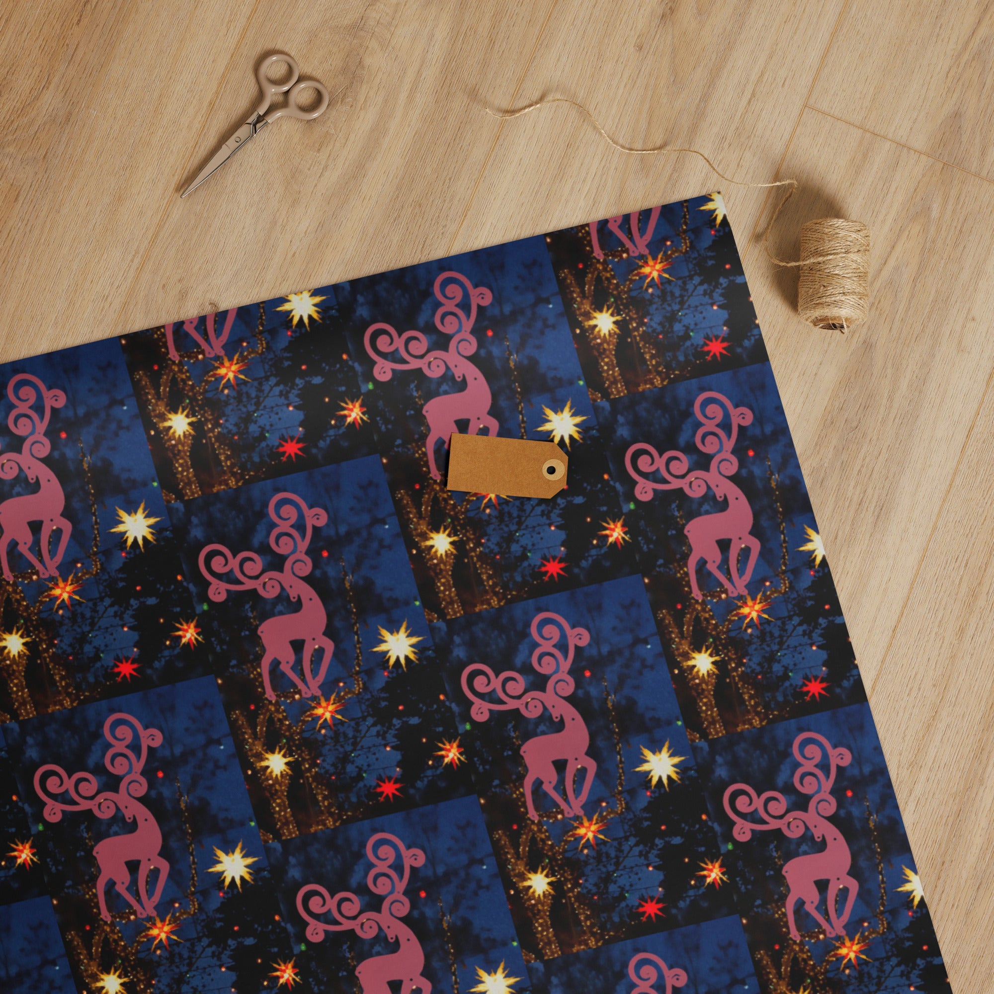 Decorative paper with pink deer design on a wooden surface with scissors.