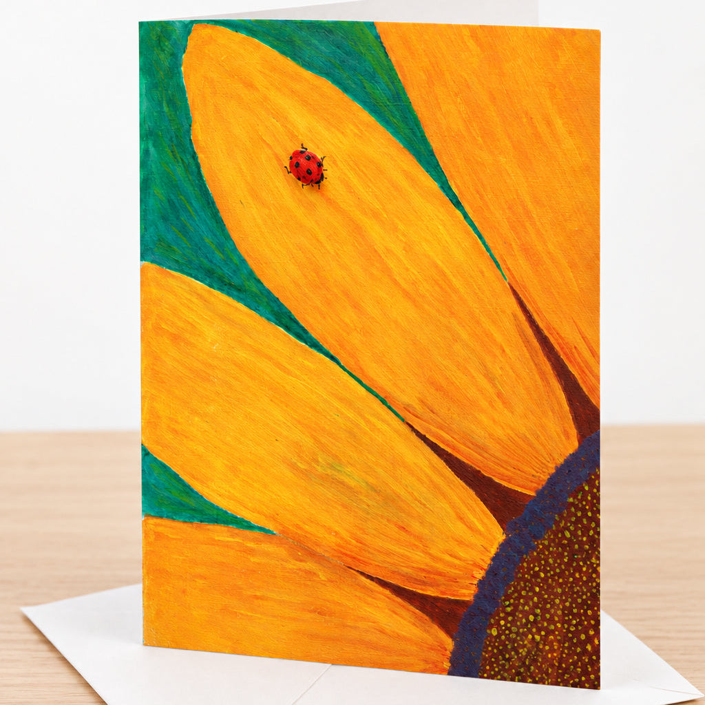 Close-up of a sunflower with a ladybug on an orange petal on a greeting card