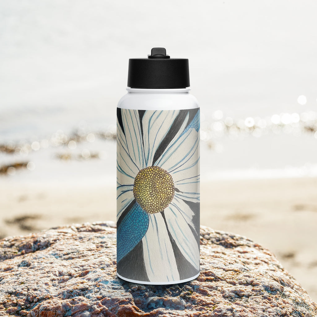 Water bottle with floral and dragonfly wings design on a rock by a beach