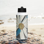 Water bottle with floral and dragonfly wings design on a rock by a beach