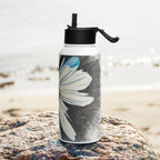 Water bottle with floral design on a rock by the beach